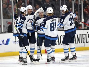 Blake Wheeler (26), Mark Scheifele (55), Patrik Laine (29) and Kyle Connor (81) congratulate Neal Pionk (4) of the Winnipeg Jets after his goal during the second period of a game against the Anaheim Ducks at Honda Center on Friday.