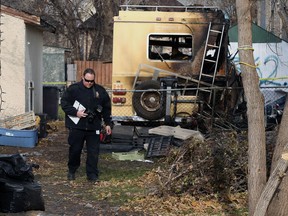 A forensics officer walks in the yard where a fire in a motor home caused a propane tank to explode in the backlane of William Newton Avenue, between Stadacona and Allan streets, in Winnipeg on Sunday. Police were in the same area for a shots fired call late Saturday afternoon that left one man in hospital in stable condition.