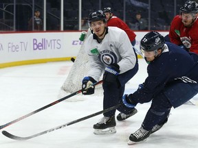 Jack Roslovic (left) plays the puck past Gabriel Bourque (57) during Winnipeg Jets practice at Bell MTS Place on Monday.