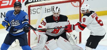 Winnipeg Jets forward Mathieu Perreault (left) tries to tip a shot past New Jersey Devils goaltender Mackenzie Blackwood with Will Butcher defending in Winnipeg on Tues., Nov. 5, 2019. Kevin King/Winnipeg Sun/Postmedia Network