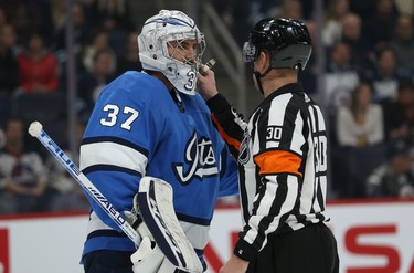Winnipeg Jets goaltender Connor Hellebuyck appeals to referee Kendrick Nicholson to go to the bench for a new mask during NHL action against the New Jersey Devils in Winnipeg on Tues., Nov. 5, 2019. Kevin King/Winnipeg Sun/Postmedia Network