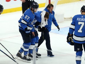 Jets’ Bryan Little is helped off the ice by teammate Nikolaj Ehlers and a member of the team’s medical staff on Tuesday night at the Bell MTS Centre.  It was Ehlers’ slap shot that struck Little in the face and sent him to hospital for two days.  Kevin King/Winnipeg Sun