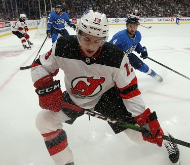 New Jersey Devils centre Nico Hischier (centre) turns away from Winnipeg Jets defenceman Neal Pionk in Winnipeg on Tues., Nov. 5, 2019. Kevin King/Winnipeg Sun/Postmedia Network