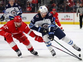 DETROIT, MICHIGAN - DECEMBER 12: Kyle Connor #81 of the Winnipeg Jets tries to avoid the stick of Filip Hronek #17 of the Detroit Red Wings during the first period at Little Caesars Arena on December 12, 2019 in Detroit, Michigan. (Photo by Gregory Shamus/Getty Images)