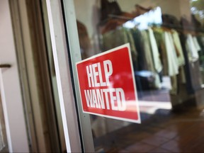 A help wanted sign is seen in the window of a store.