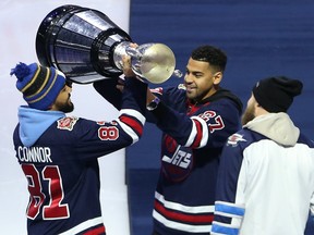 Andrew Harris (right) hands the Grey Cup to Nic Demski (left), as Chris Streveler watches. The three Winnipeg Blue Bombers took part in a ceremonial faceoff prior to the Winnipeg Jets game against the Dallas Stars in Winnipeg on Tuesday night. (Kevin King/Winnipeg Sun)