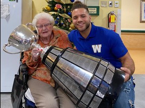 Brady Oliveira of the Blue Bombers poses with 107-year-old Roby Fraser and the Grey Cup yesterday at Oakview Place. (Paul Friesen, Winnipeg Sun)