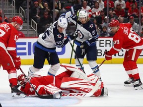 Red Wings goaltender Jonathan Bernier lays on top of the puck after a second period save next to Mark Scheifele (left) and Kyle Connor  of the Winnipeg Jets at Little Caesars Arena in Detroit on Thursday. (Getty Images)