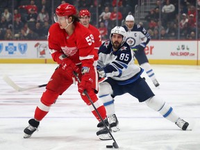 Red Wings’ Tyler Bertuzzi looks to pass the puck as Winnipeg Jets’ Mathieu Perreault gives chase in Detroit last night. (Getty images)