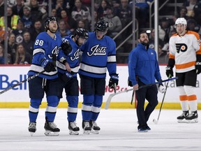 Jets’ Mathieu Perreault (centre) is helped off the ice by teammates Nathan Beaulieu (left) and Andrew Copp after being injured against the Philadelphia Flyers earlier this month. Perreault returned to the ice on Saturday in a non-contact jersey. (CP FILES)