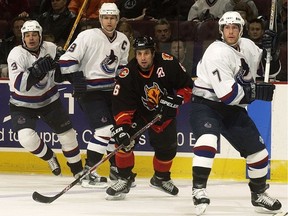 Vancouver Canucks Brent Sopel, left, Markus Naslund, centre, and Brendan Morrison surround Bob Boughner of the Calgary Flames in NHL action in December of 2002.