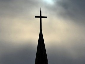 The sun is obscured by clouds behind the steeple and cross of a Lutheran church in this file photo. (Postmedia file photo)