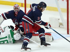 Winnipeg Jets defenceman Tucker Poolman (right) collects the puck as Dallas Stars centre Joe Pavelski lands in front of goaltender Connor Hellebuyck in Winnipeg on Tues., Dec. 3, 2019. Kevin King/Winnipeg Sun/Postmedia Network