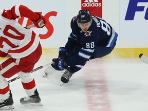 Jets defenceman Nathan Beaulieu (right) hammers on the brakes after turning the puck over to the Red Wings’ Christoffer Ehn last night.  Kevin King/Winnipeg Sun