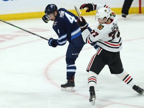 Winnipeg Jets defenceman Neal Pionk (left) buckles Chicago Blackhawks centre Kirby Dach with a shoulder check in Winnipeg on Thursday. Kevin King/Winnipeg Sun/Postmedia Network