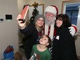 Kimberlee Chester (left) takes a selfie with Santa, her son Cadon, 6, and another woman after a key ceremony at their Habitat for Humanity home on Stella Avenue in Winnipeg on Monday.