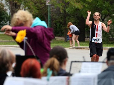 Gord Funk from Steinbach does a little conducting of his own as he runs past the 'Marathon band' in Harrow Park during the Manitoba Marathon on Sun., June 16, 2019. Kevin King/Winnipeg Sun/Postmedia Network ORG XMIT: POS1906161503460107