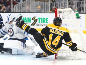 Chris Wagner #14 of the Boston Bruins trips over Laurent Brossoit #30 of the Winnipeg Jets during the first period at TD Garden. Photo by Maddie Meyer/Getty Images