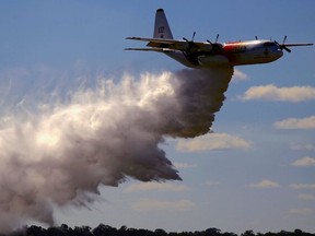 A television reporter stands in front of a Large Air Tanker (LAT) C-130 Hercules as it drops a load of around 15,000 litres during a display by the Rural Fire Service ahead of the bushfire season at RAAF Base Richmond Sydney, Australia, September 1, 2017.
