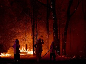 A Rural Fire Service firefighter conducts mopping up near the town of Sussex Inlet on Tuesday, Dec. 31, 2019 in Sydney, Australia.