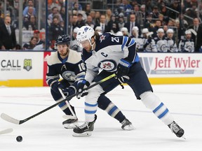 Jets’ Blake Wheeler grabs a loose puck as Blue Jackets’ Alexander Wennberg trails on Wednesday night in Columbus. (USA TODAY SPORTS)