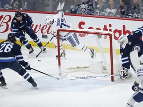 Winnipeg Jets goaltender Connor Hellebuyck (37) gets caught behind the net as Toronto Maple Leafs' Adam Brooks (77) steals the puck and passes to William Nylander (88) who takes the shot to score last night.  THE CANADIAN PRESS/John Woods