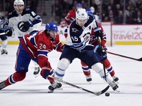 Montreal Canadiens forward Phillip Danault (24) pokes the puck away from Winnipeg Jets forward Mark Scheifele (55) during the third period at the Bell Centre.
