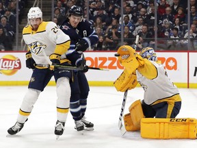 Jan 12, 2020; Winnipeg, Manitoba, CAN;  Nashville Predators goaltender Juuse Saros (74) makes a glove save as Nashville Predators defenseman Jarred Tinordi (24) checks  Winnipeg Jets center Mark Scheifele (55) in the second period  at Bell MTS Place. Mandatory Credit: James Carey Lauder-USA TODAY Sports