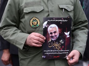 An Iranian policeman man holds a picture of late General Qassem Soleimani, head of the elite Quds Force, who was killed in an air strike at Baghdad airport, as people gather to mourn him in Tehran, Iran January 4, 2020.