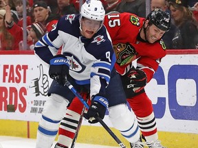CHICAGO, ILLINOIS - JANUARY 19: Andrew Copp #9 of the Winnipeg Jets and Zack Smith #15 of the Chicago Blackhawks battle for the puck behind the net at the United Center on January 19, 2020 in Chicago, Illinois.