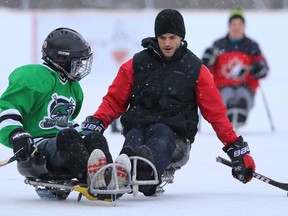 Sean Gilmour (right) plays sledge hockey with a youngster at Dakota Community Centre in Winnipeg on Wed., Jan. 29, 2020 after the club formally announced a Learn to Play Sledge Hockey program on its fully accessible rink. Kevin King/Winnipeg Sun/Postmedia Network