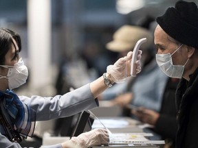 A passenger receives a temperature check before taking a flight bound for Wuhan at Spring Airlines' check-in counter at Haneda airport on January 31, 2020 in Tokyo, Japan.