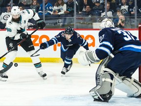 Sharks defenceman Brent Burns tries to settle the puck past Jets defenceman Dmitry Kulikov during the first period  at Bell MTS Place last night.  Terrence Lee/USA TODAY Sports