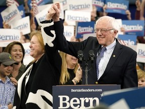 Democratic presidential candidate Sen. Bernie Sanders holds the hand of his spouse Jane O'Meara Sanders as he takes the stage during a primary night event in Manchester, New Hampshire, on Tuesday, Feb. 11, 2020.
