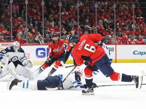 Capitals’ Michal Kempny shoots the puck as Jets’ Tucker Poolman blocks the path to netminder Laurent Brossoit during the first period of Tuesday night’s game at Capital One Arena in Washington. (USA TODAY SPORTS)