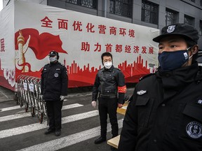 A Chinese man who is a member of the neighbourhood committee, centre, and security guards wear protective masks as they control entry and exit from a residential area on February 20, 2020 in Beijing, China. (Kevin Frayer/Getty Images)