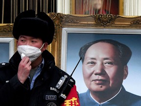 A security guard wearing a facemask to help stop the spread of a deadly virus which began in Wuhan, stands beside a portrait of the late Chinese communist leader Mao Zedong at a shopping centre in Beijing on January 27, 2020. (NOEL CELIS/AFP via Getty Images)