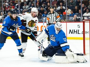 Feb 9, 2020; Winnipeg, Manitoba, CAN;  Winnipeg Jets goalie Connor Hellebuyck (37) makes a save with Chicago Blackhawks forward Jonathan Toews (19) and Winnipeg Jets defenseman Sami Niku (8) looking for the rebound during the first period at Bell MTS Place. Mandatory Credit: Terrence Lee-USA TODAY Sports ORG XMIT: USATSI-405851