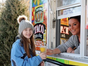 Kaylee Sprong of Fresh Squeezed Lemonade passes a lemonade to Ava Chandler at the 51st annual Festival du Voyageur in Winnipeg, Man., on Sunday, Feb. 23, 2020. Temperatures  were quite mild for enjoying lemonde on the final day of Festival du Voyageur for 2020.