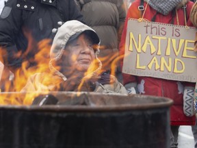 Aamjiwnaang First Nation elder Misquakeeshick sits near a fire barrel on the CP tracks at Waterloo Street and Pall Mall Street in London, Ont. on Friday Feb. 28, 2020. (Derek Ruttan/The London Free Press/Postmedia Network)