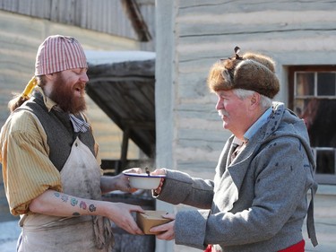 Murray Gillespie, who is a clerk at the trading post inside Fort Gilbraltar, trades a piece of bannock with James Young, who is portraying a loyalist from the American revolution for a bowl of stew on the final day of the 51st annual Festival du Voyageur in Winnipeg, Man., on Sunday, Feb. 23, 2020.