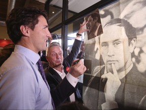 Liberal leader Justin Trudeau looks at a poster of his late father, former Prime Minister Pierre Trudeau, during a campaign stop at a coffee shop in Sainte-Therese, Quebec, October 15, 2015.  REUTERS/Chris Wattie/File Photo
