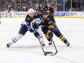 BUFFALO, NY - FEBRUARY 23: Dylan DeMelo #12 of the Winnipeg Jets and Sam Reinhart #23 of the Buffalo Sabres go after a loose puck during the second period at KeyBank Center on February 23, 2020 in Buffalo, New York.