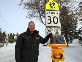 Chuck Lewis poses for a photograph with a solar-powered flashing light he installed on a school zone warning sign on Bedson Street, near Winnipeg Mennonite Elementary School, in Winnipeg on Thursday, Feb. 6, 2020.