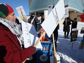 A woman holds signs during a rally organized by the Palestine-Manitoba Solidarity Group to protest United States president Donald Trump's 'Deal of the Century' outside the Canadian Museum for Human Rights in Winnipeg on Sunday.