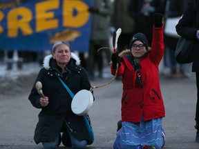 Women kneel at Portage and Main in Winnipeg as part of solidarity action with the Wet'suwet'en Hereditary Chiefs and peoples in their land dispute, on Monday.