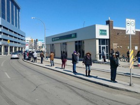 People lined up for a bank on the corner of Notre Dame Avenue and Sherbrook Street practise social distancing on Friday. James Snell/Winnipeg Sun