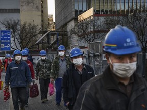 Chinese construction workers wear protective masks as they leave a site at the end of the work day on March 20, 2020 in Beijing, China. (Kevin Frayer/Getty Images)