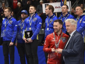Team Alberta skip Brendan Bottcher, left, and his team look on as Team Newfoundland and Labrador skip Brad Gushue, right, is presented with an award during the medal ceremony the Brier in Kingston, Ont., on Sunday, March 8, 2020.
