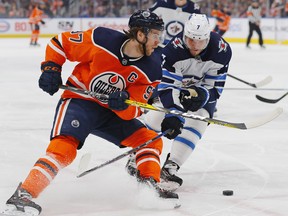 Oilers forward Connor McDavid (left) tries to move the puck around Jets defencemen Dmitry Kulikov during the first period at Rogers Place in Edmonton last night.  Perry Nelson/USA TODAY Sports